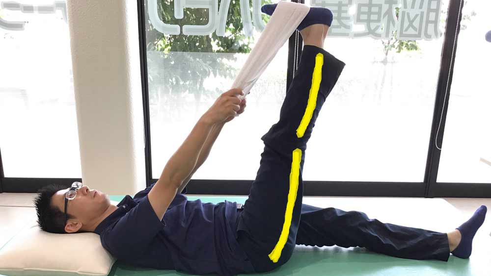 仰向けに寝て、両手で持ったタオルで片脚の裏をひっかけて上に持ち上げてストレッチ