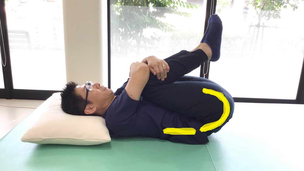仰向けになり両膝を胸に抱え込んでストレッチ
